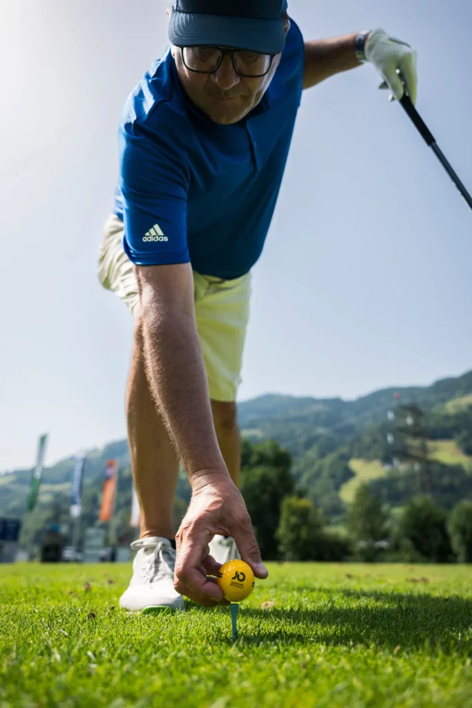 Golfer legt einen gelben Ball auf ein Tee am Abschlag